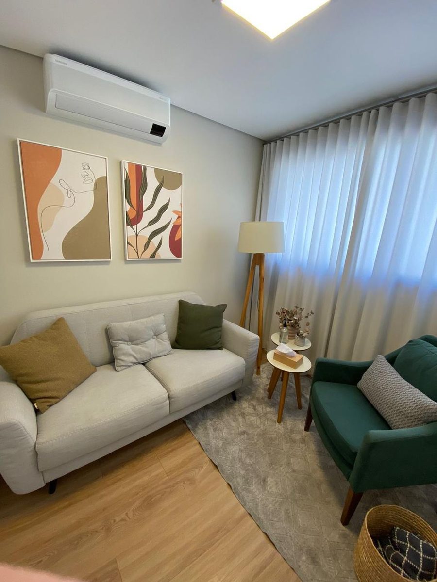 Sala de atendimento presencial, com sofá, poltrona e luminária
